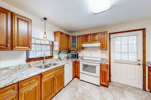Kitchen features a stainless steel sink, microwave, and double oven, with a window and blinds.