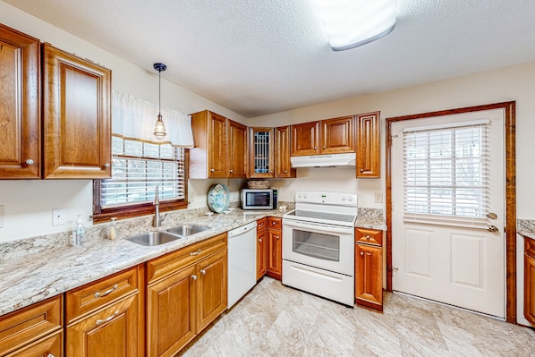 Kitchen features a stainless steel sink, microwave, and double oven, with a window and blinds.
