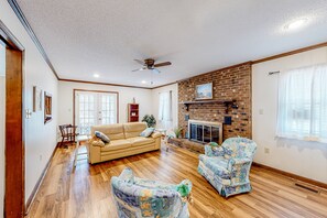 Relax in this inviting living room with a brick fireplace, sofa, and armchairs.
