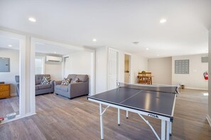 Ein geräumiger Wohnbereich mit Tischtennisplatte, Sofas und einem Holzes Esstisch.