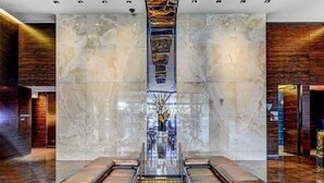 A modern lobby with marble walls, a central staircase, and leather seating. - Luxe Condo l Balcony Strip View l NO RESORT FEES l FREE PARKING (Las Vegas)