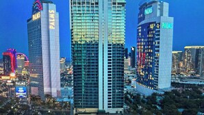 A high-rise building with "PALMS" signage, surrounded by other tall buildings and a cityscape at dusk. - Luxe Condo l Balcony Strip View l NO RESORT FEES l FREE PARKING (Las Vegas)
