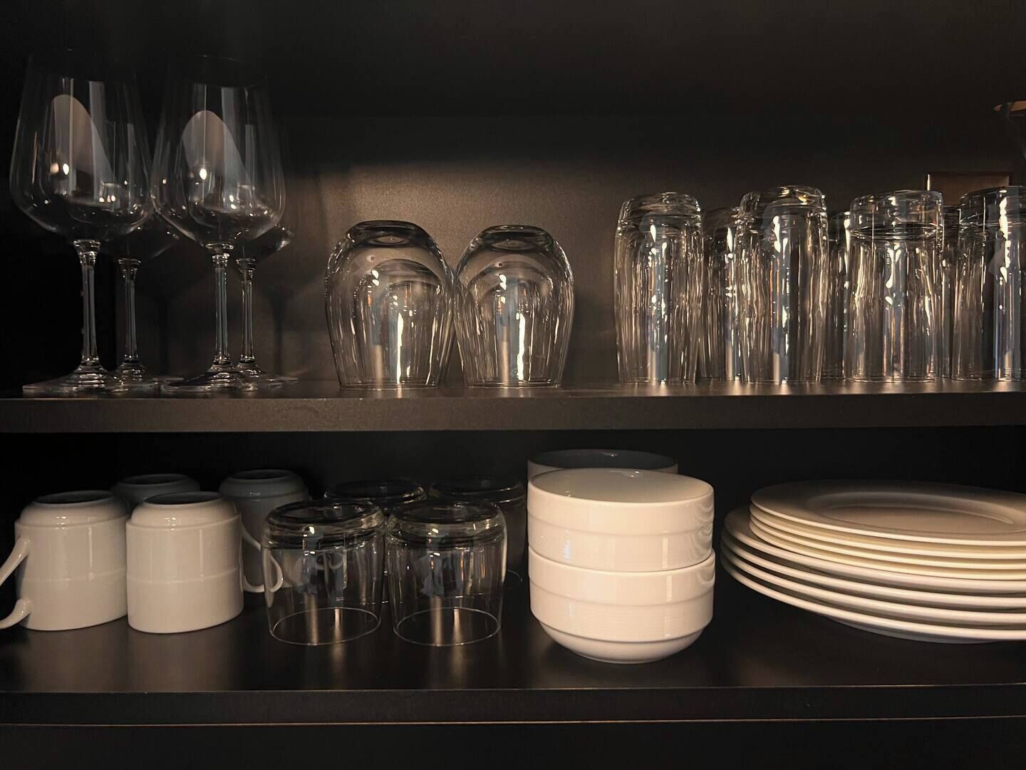 A kitchen shelf with various glassware and dishes.