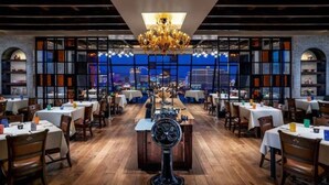 A restaurant with a central chandelier, wooden floors, and tables set for dining. - Luxe Condo l Balcony Strip View l NO RESORT FEES l FREE PARKING (Las Vegas)