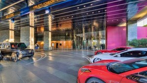 A modern building entrance with a 'Welcome' sign, a glass facade, and several cars parked in front. - Luxe Condo l Balcony Strip View l NO RESORT FEES l FREE PARKING (Las Vegas)