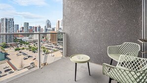 Un balcon offrant une vue sur le paysage urbain, avec notamment des immeubles de grande hauteur et un parking.