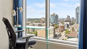 Un fauteuil de bureau moderne placé devant une grande fenêtre donnant sur un paysage urbain.