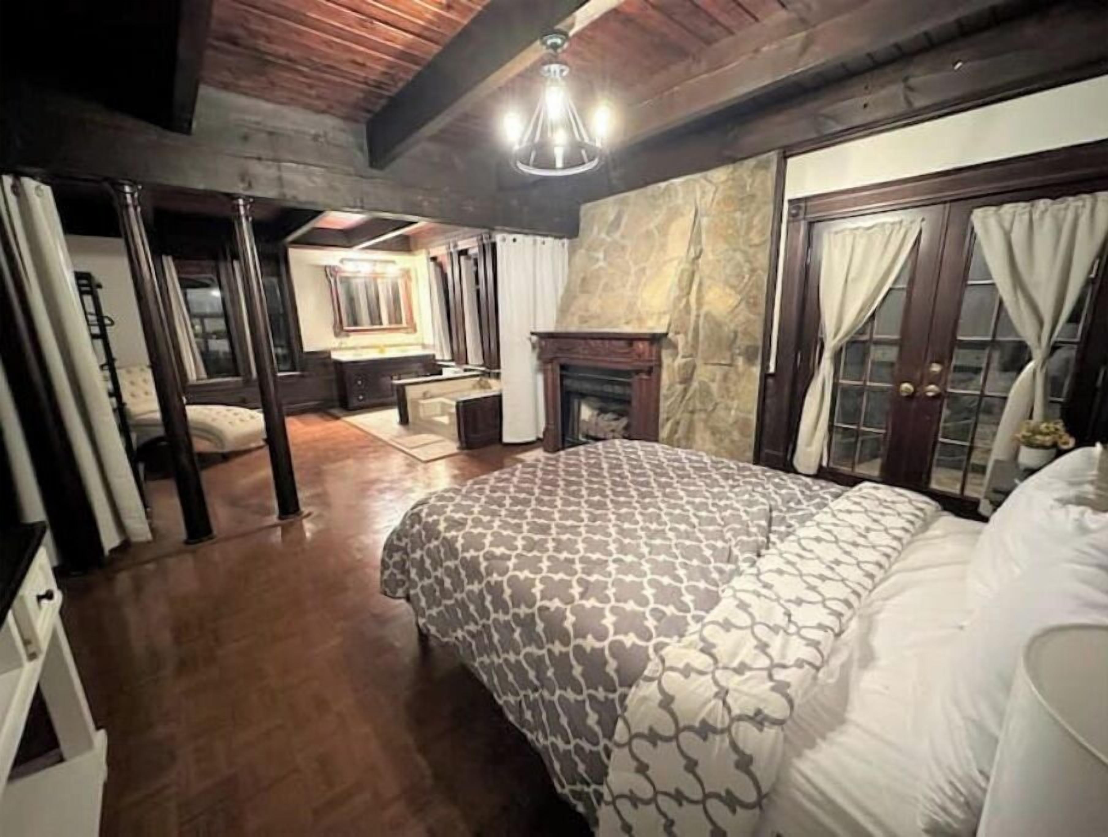 Ein Schlafzimmer mit einem gemusterten Bettbezug, einem Kamin und einer Steinwand.