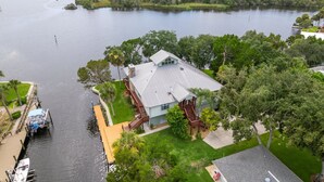 Una casa con un molo, immersa nel verde e affacciata su un'ampia distesa d'acqua.
