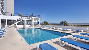 A swimming pool with lounge chairs, a staircase, and a view of the ocean.