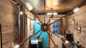 Une cuisine moderne avec des murs en bois, un îlot central et un luminaire suspendu doté de plusieurs ampoules.