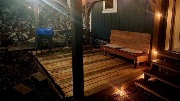 Un espace extérieur accueillant, aménagé avec un banc en bois et une table, entouré de murs en pierre et de poutres en bois.