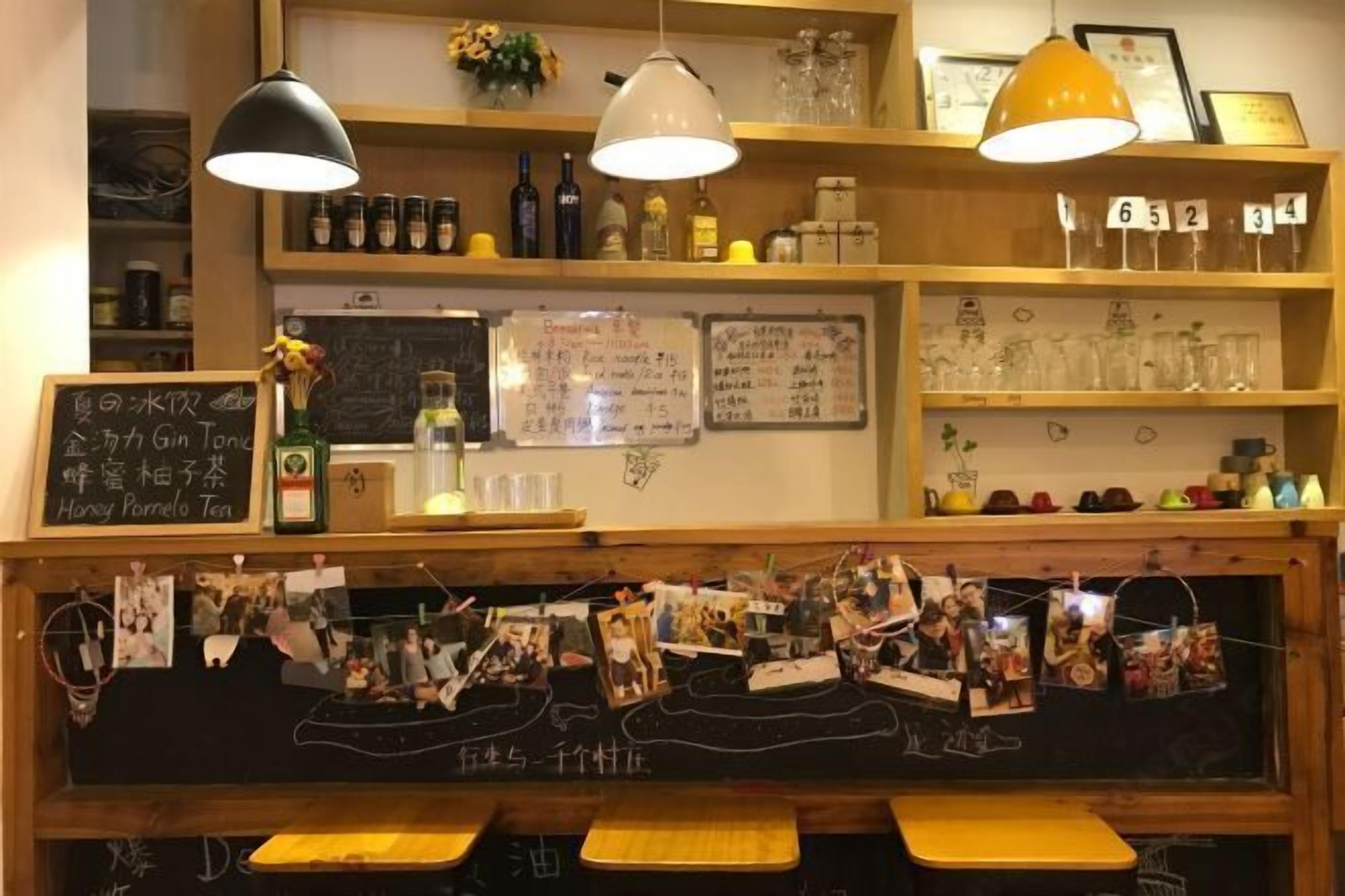 Un café avec des étagères en bois, des lampes suspendues et un menu écrit à la craie.