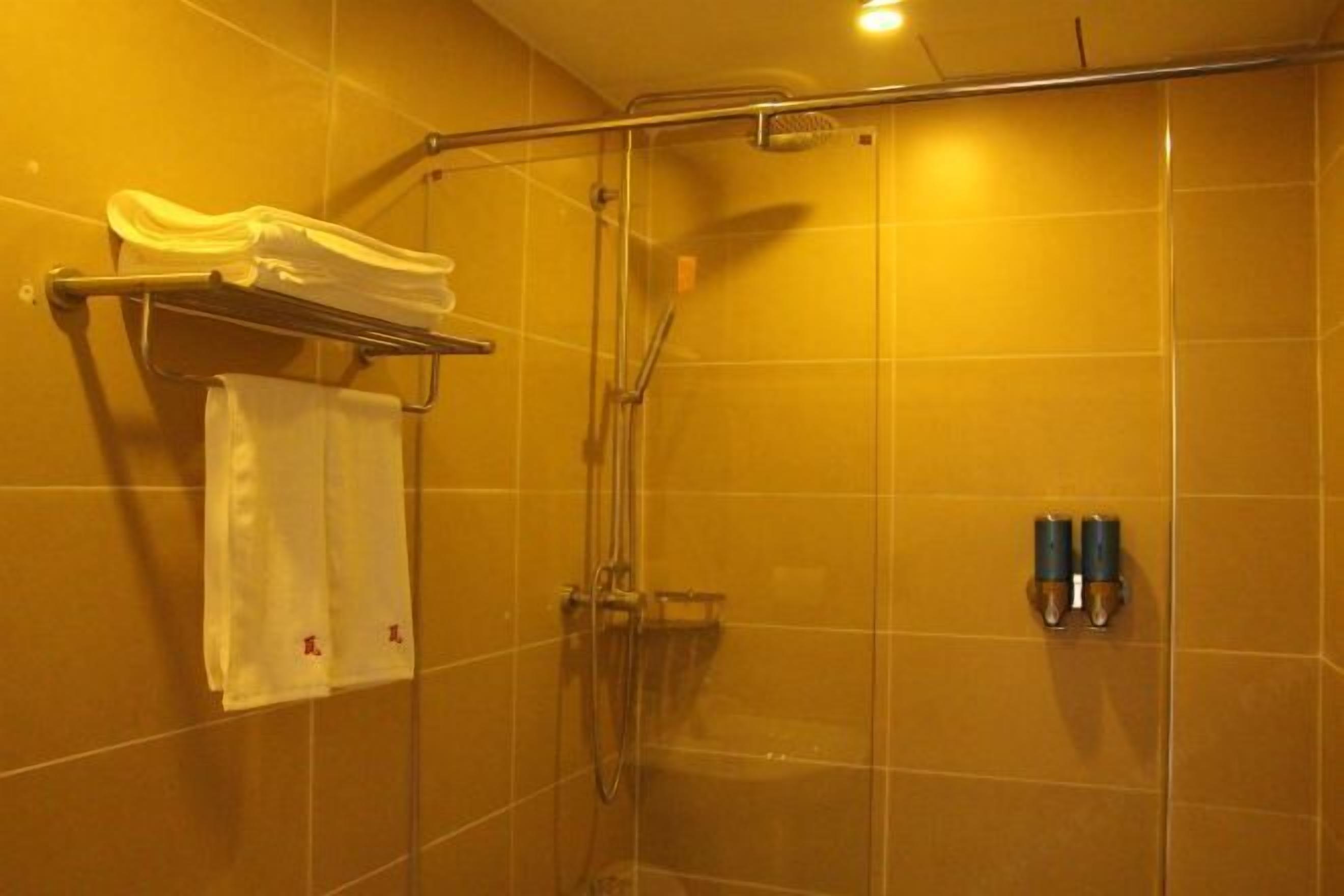 A shower area with a glass door, a towel rack with a towel, and two bottles on the wall.