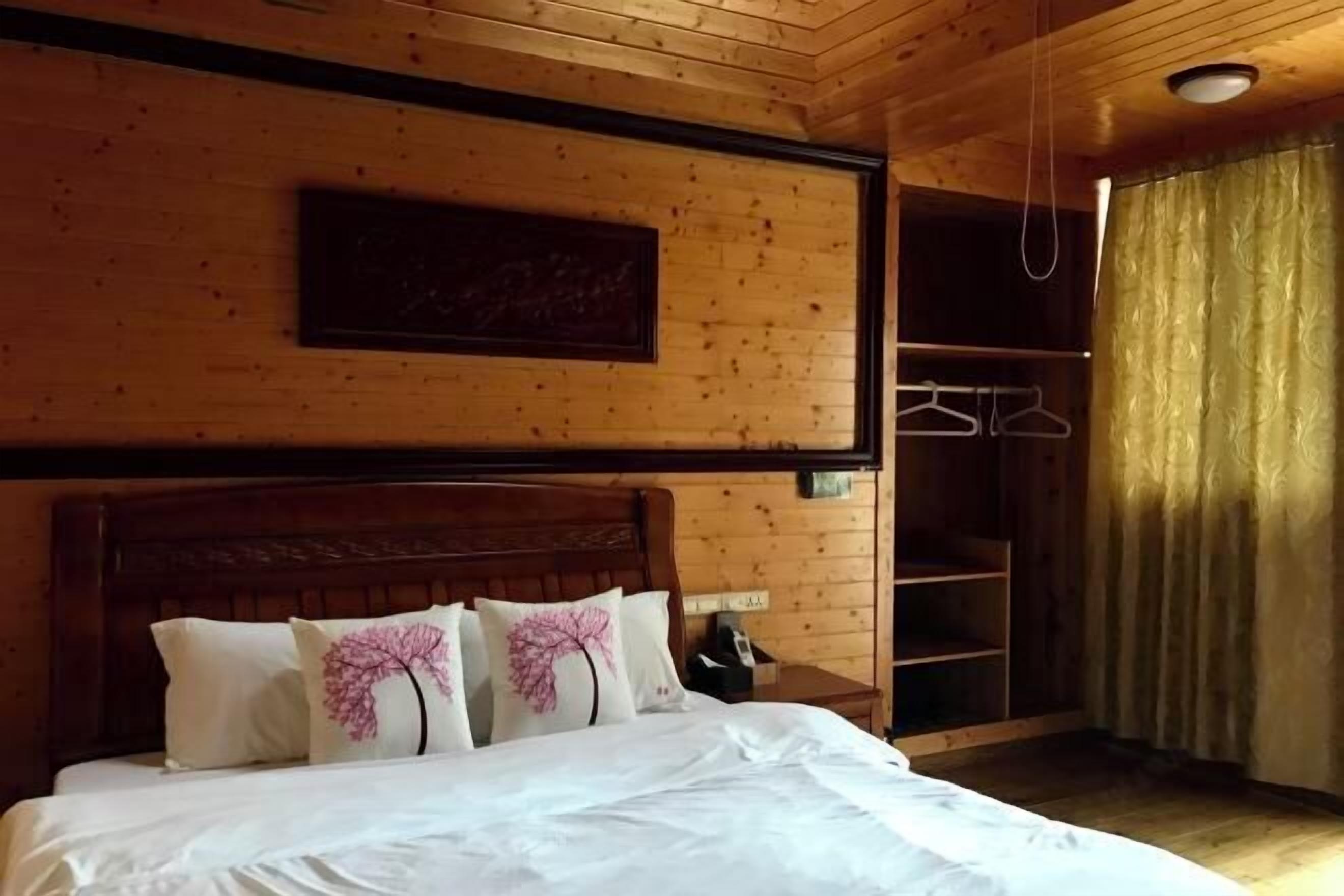 A wooden-paneled room with a bed, a coat rack, and a framed picture on the wall.