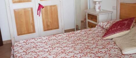 Un dormitorio con cama, armario, mesita de noche y espejo.