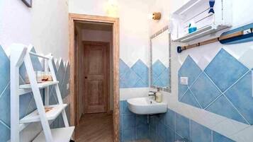 Une salle de bain avec des murs recouverts de carreaux bleus, un lavabo blanc et une porte en bois.