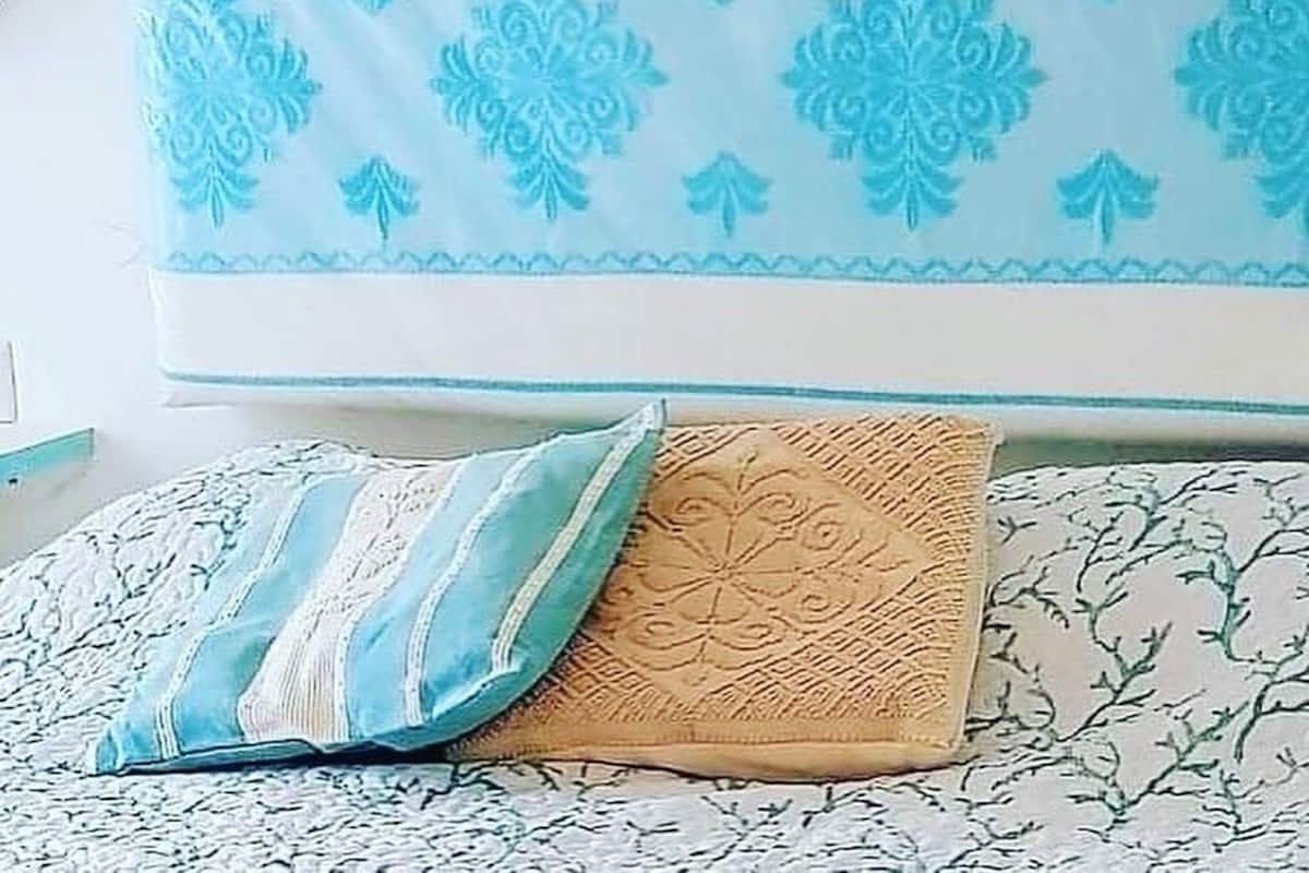 A bed with a patterned bedspread, a pillow, and a headboard with a decorative design.