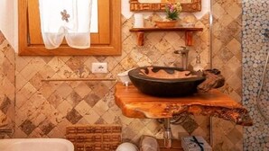 A bathroom with a wooden vanity, a large mirror, and a sink with a unique basin design. - Tenuta Petra manna  (Palau)