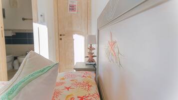 Una camera da letto con un letto, una cassettiera e una porta che dà su un bagno.