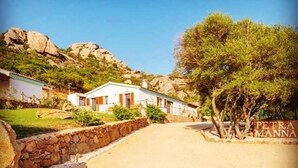 A rural road leading to a white building with a stone wall on one side. - Tenuta Petra manna  (Palau)