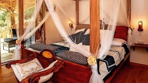 A room with a four-poster canopy bed, wooden flooring, and a view of the outdoors. - Tenuta Petra manna  (Palau)