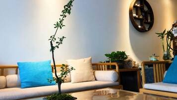 A living room with a sofa, a coffee table, and a potted plant.