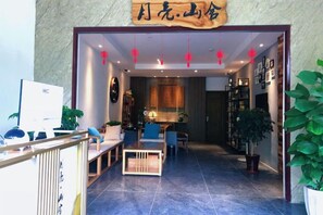 A hotel entrance with a reception desk, seating area, and a staircase leading to the upper floor. - Yangshuo Moon Villa Homestay (Yulonghe Scenic Area Branch) (Yangshuo)