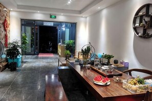 Un área de recepción con mostrador, plantas en macetas y una estantería en la pared.