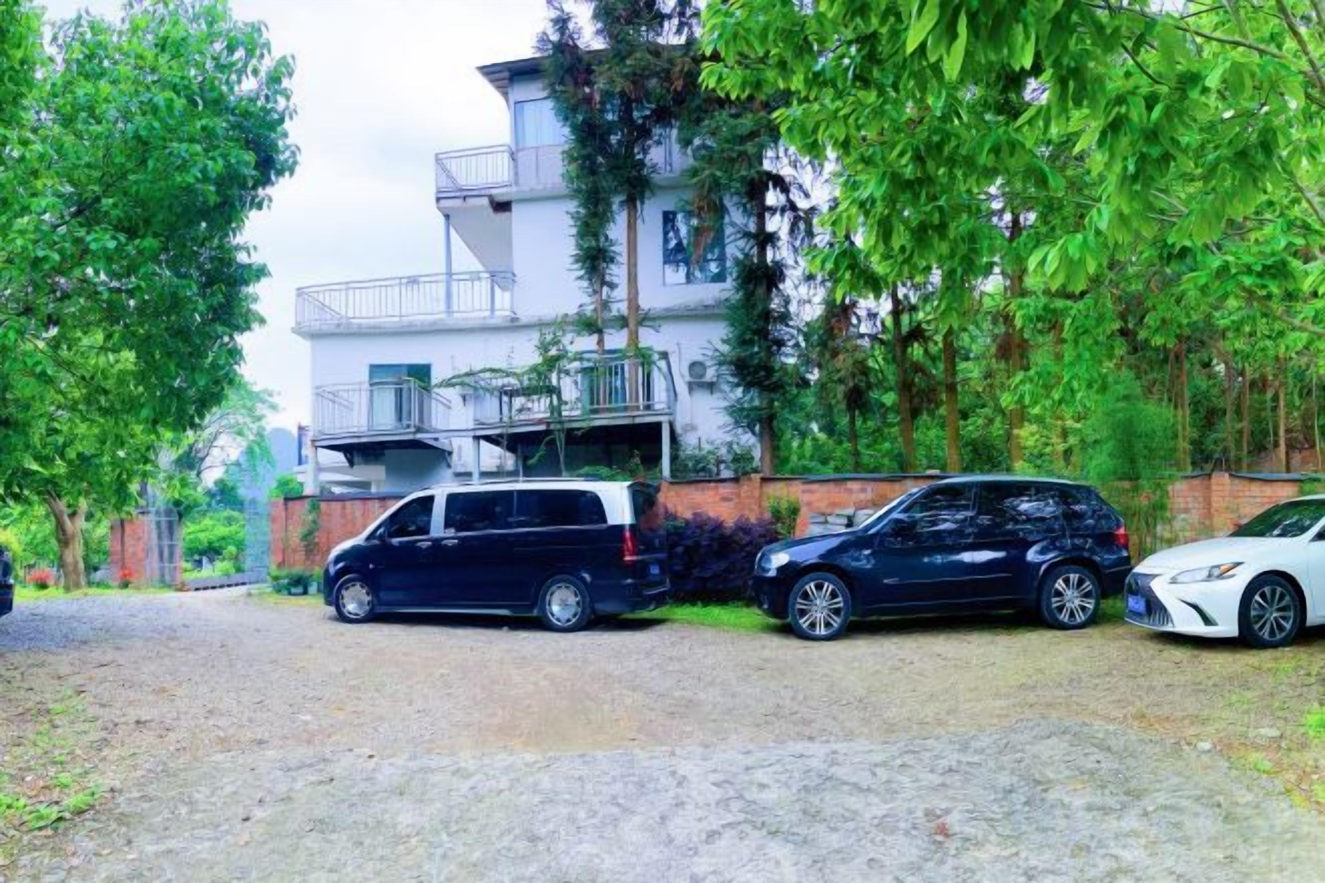 Asuinalue, jossa on kaksikerroksinen rakennus, ajotie ja parkissa olevia autoja.