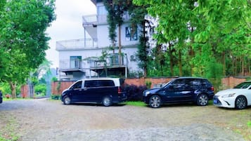 A residential area with a two-story building, a driveway, and parked cars.