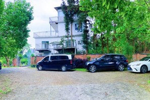Zona residencial con un edificio de dos plantas, un camino de entrada y coches estacionados.