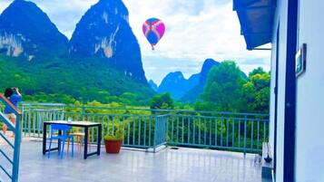 Un balcón con vistas a montañas y un globo aerostático a lo lejos.