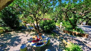 An outdoor seating area with a round table and chairs, surrounded by trees and plants.