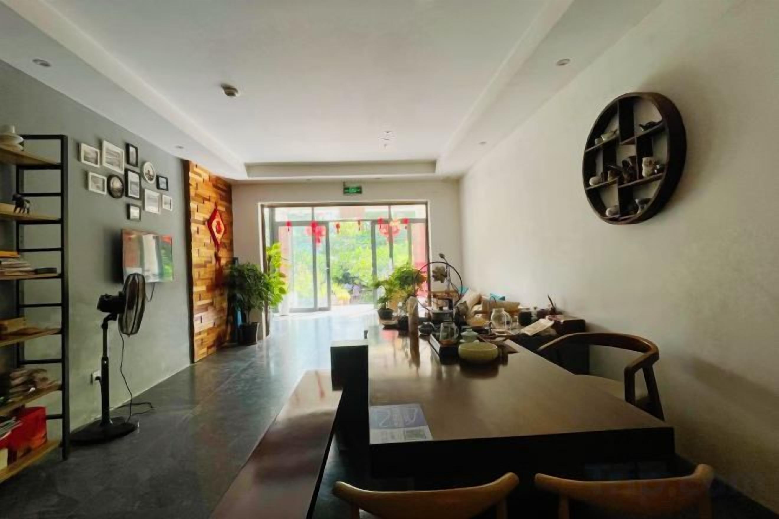 A modern hotel lobby with a long reception desk, seating area, and a large window with a view of greenery.