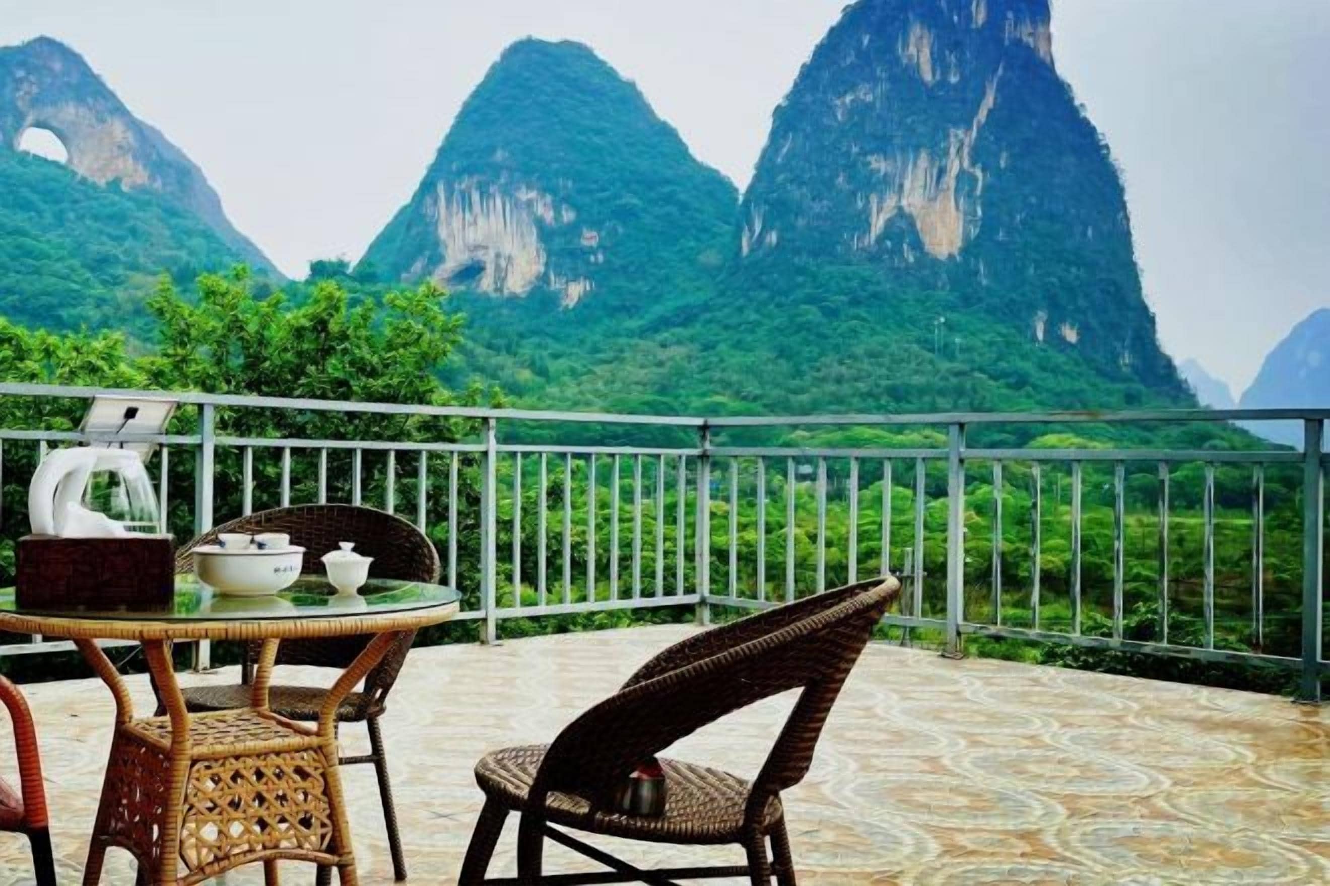 Un balcon avec une table et des chaises, donnant sur un paysage montagneux.