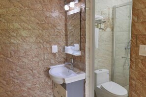 Un baño con pared de mármol, un lavamanos, un inodoro y una cabina de ducha de vidrio.