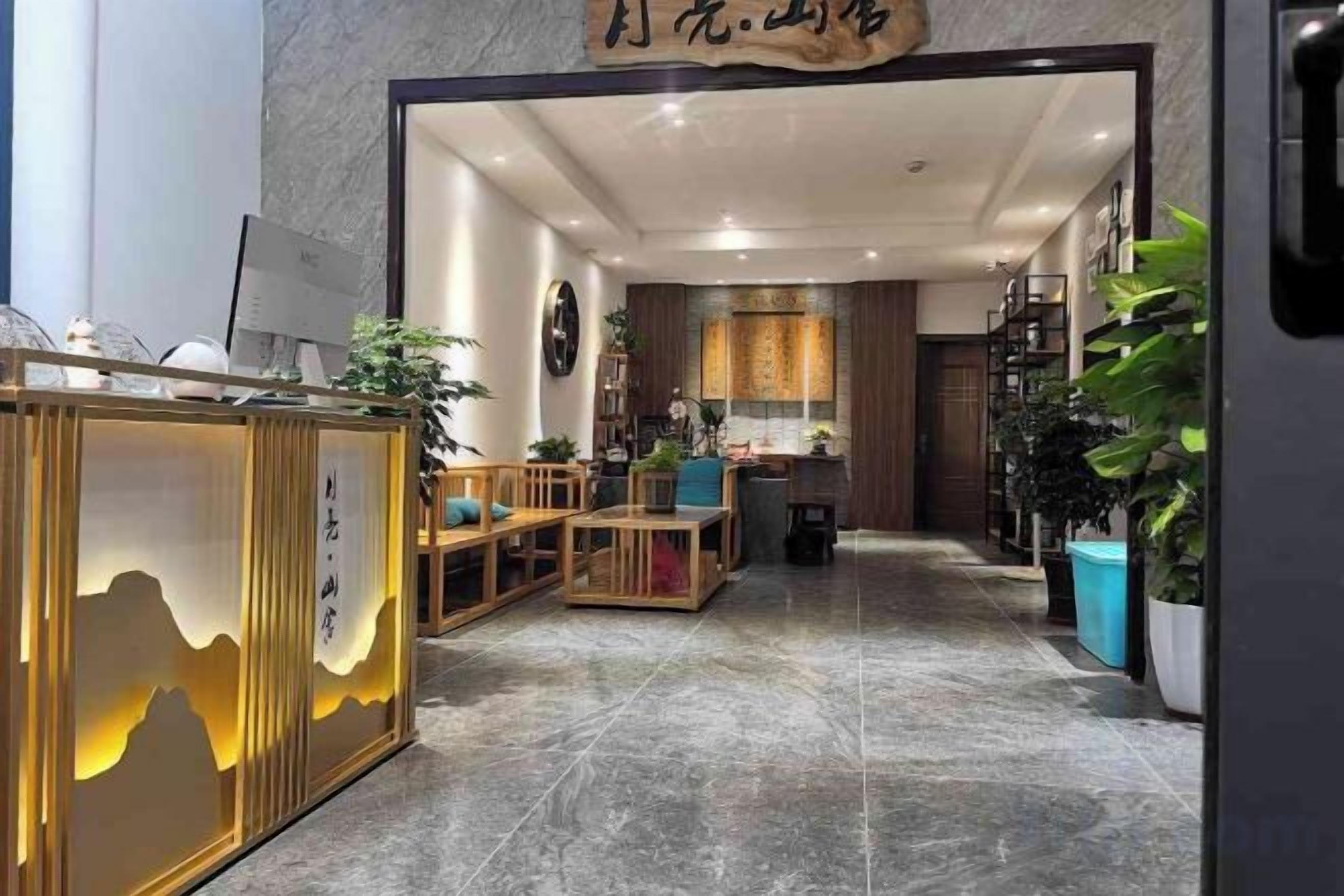 A hotel lobby with a reception desk, seating area, and a kitchen in the background.