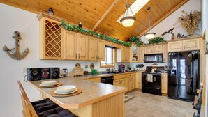 A spacious kitchen with wooden cabinets, a central island, and modern appliances. - Waubun Lake Cabin w/ Private Dock + Fire Pit! (Waubun)