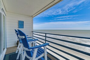 Een balkon met blauwe stoelen en uitzicht op de oceaan.