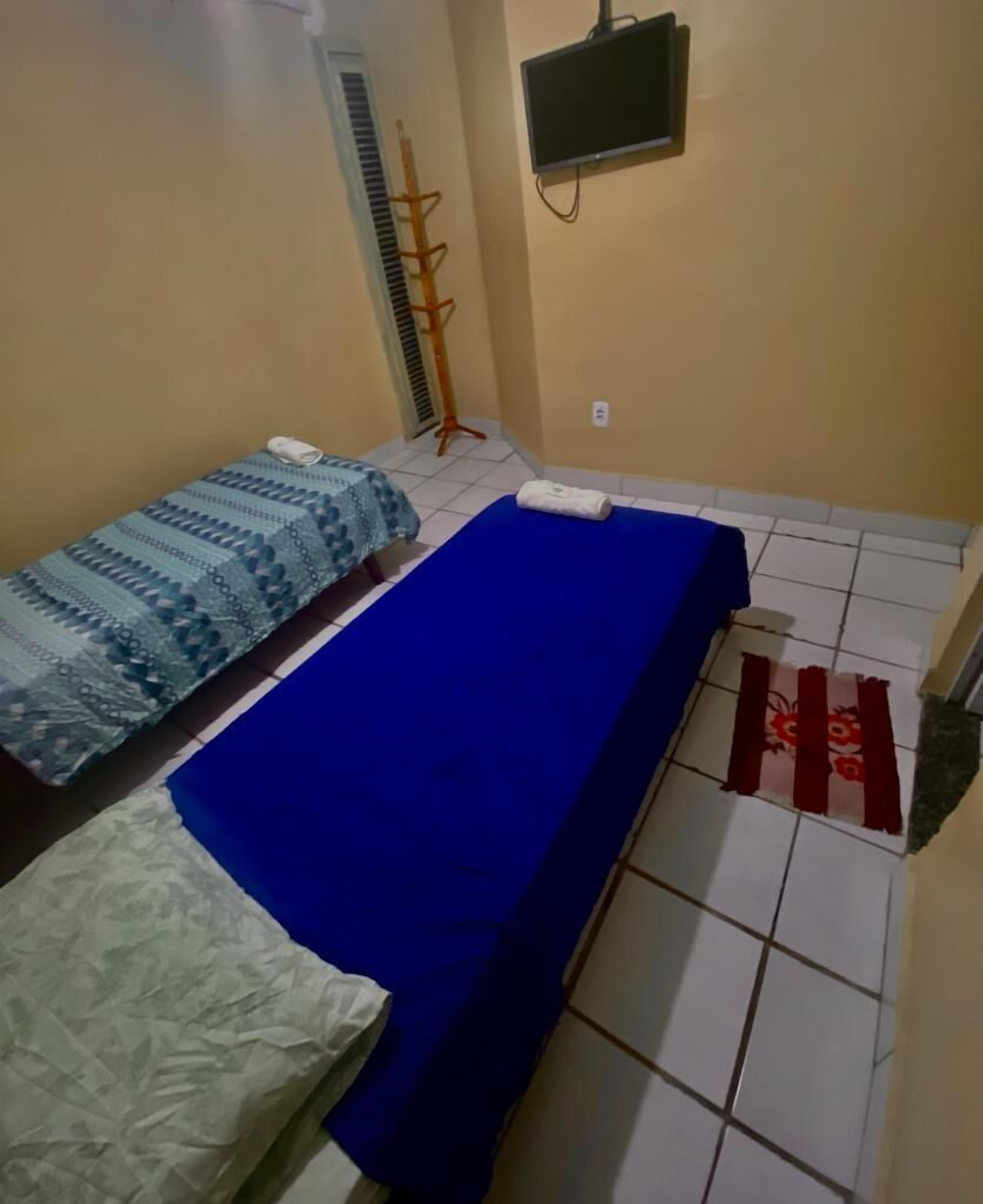Quarto pequeno e limpo com duas camas, televisão e radiador.