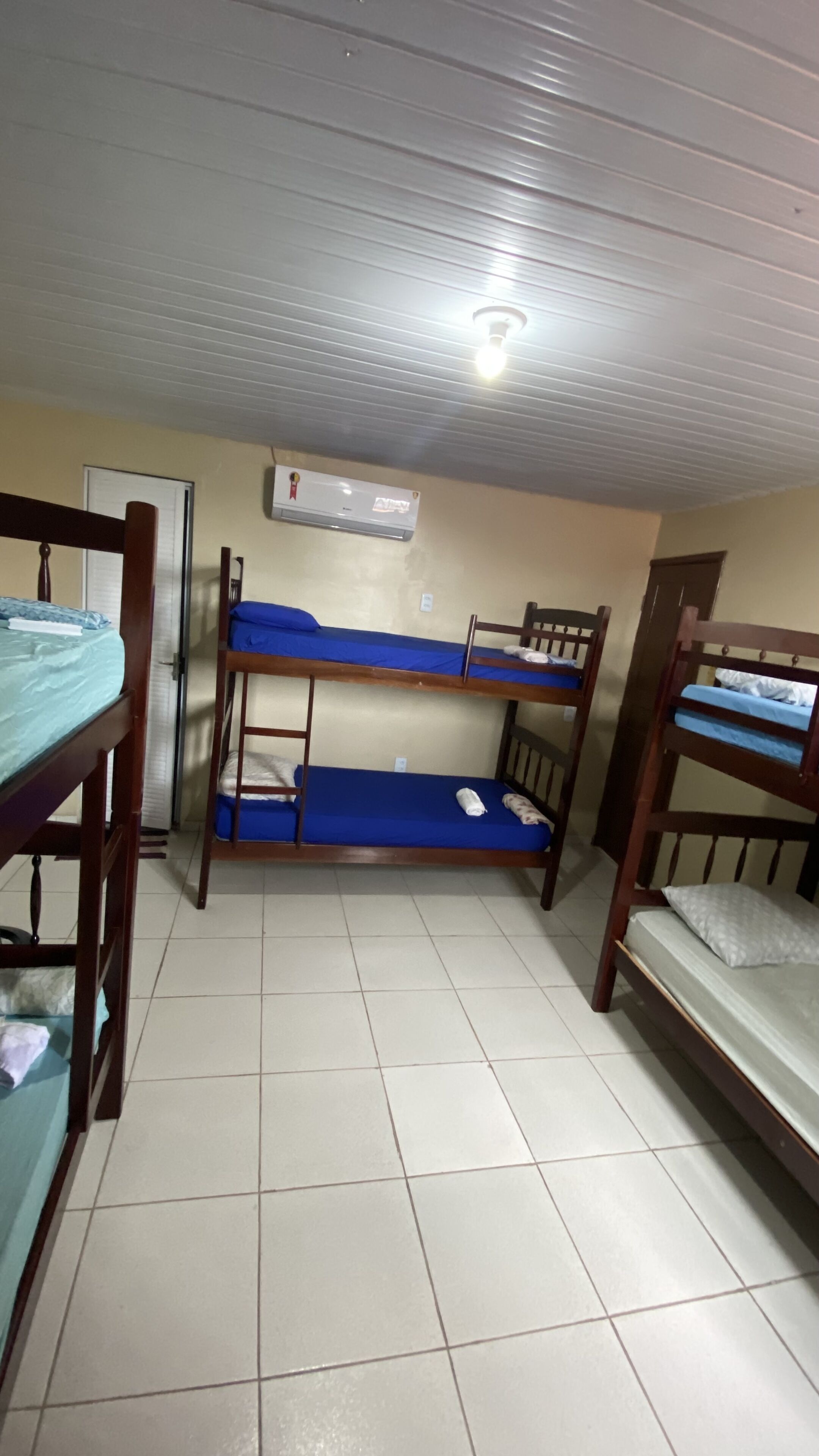 Quarto em dormitório com beliches, ventilador de teto e ar condicionado.
