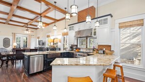 A spacious kitchen with a large island, white cabinetry, and a high ceiling with exposed beams. - WaterColor Park District - Private beach access & amenities! (Santa Rosa Beach)