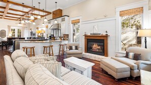 A spacious living room with a fireplace, a kitchen area, and a dining bar. - WaterColor Park District - Private beach access & amenities! (Santa Rosa Beach)