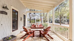 A covered porch with wooden flooring, Adirondack chairs, and a potted plant. - WaterColor Park District - Private beach access & amenities! (Santa Rosa Beach)