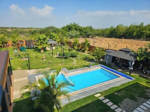 Un patio trasero residencial con piscina, zona de juegos infantiles y terraza amueblada.