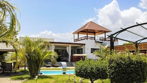 A modern building with a pool, outdoor seating, and a covered patio area.