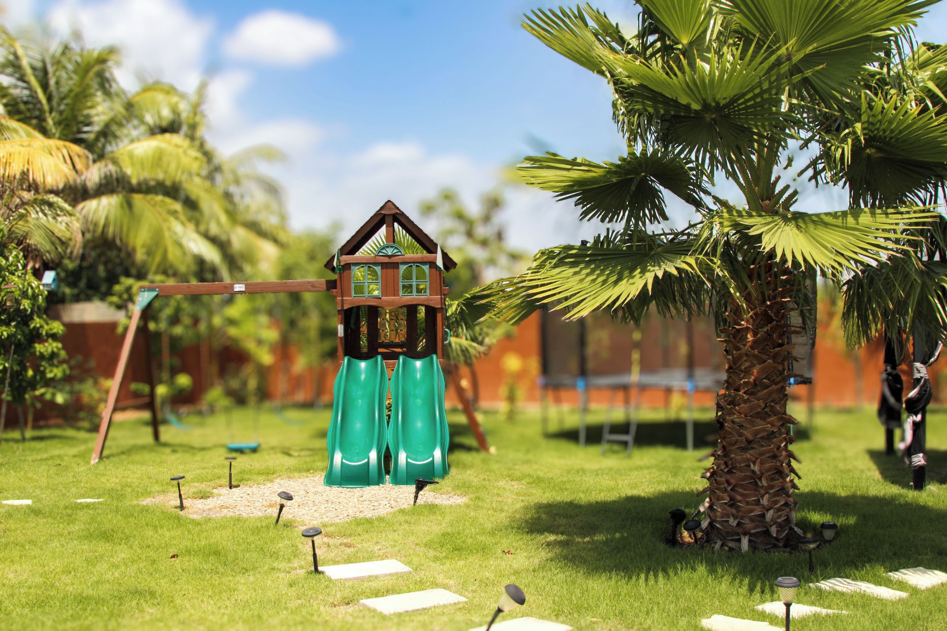 Zona de juegos infantiles con tobogán, columpios y una pequeña estructura de madera.