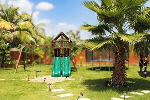 A children's play area with a slide, swings, and a small wooden structure.