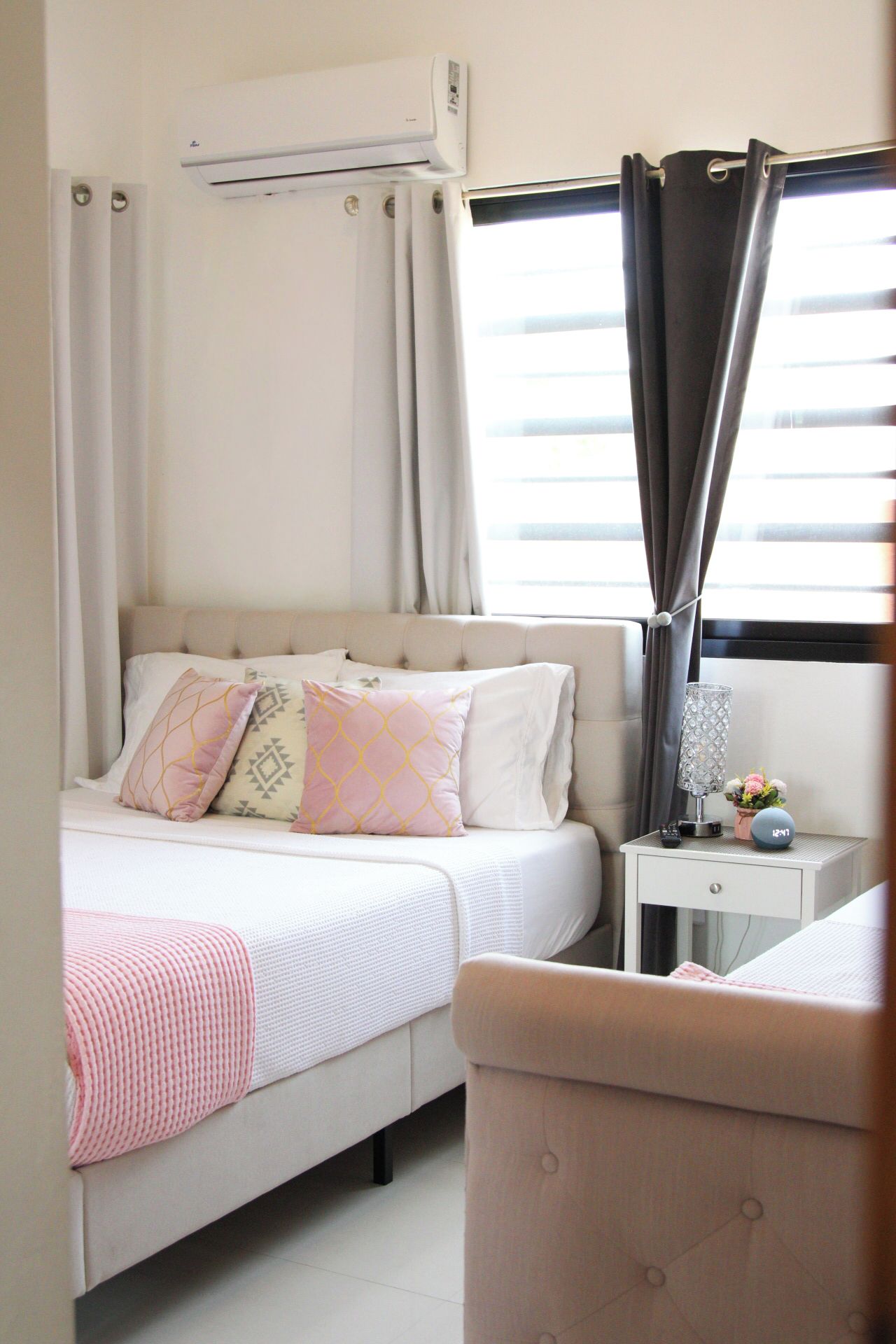 A bedroom with a bed, bedside table, lamp, and curtains.